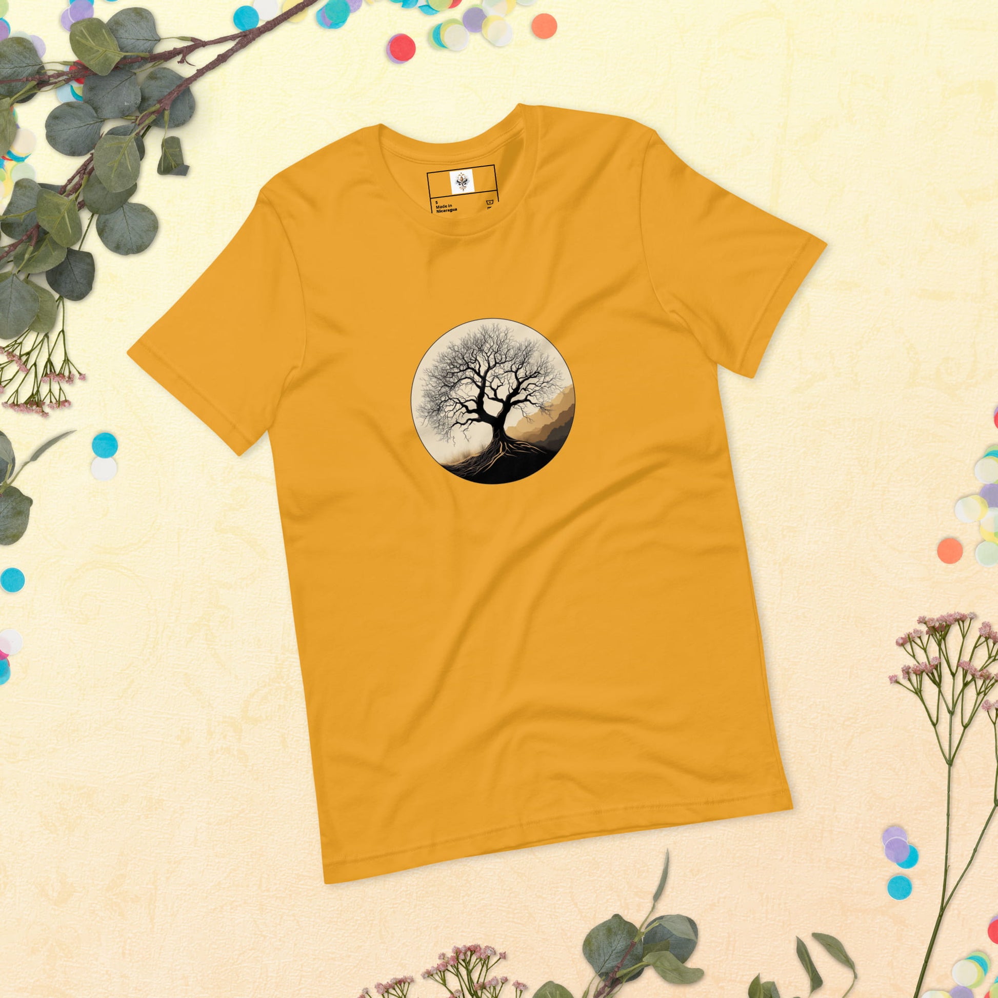 Roots of Life - Silhouette illustration of a bare tree with extensive roots, enclosed within a circle, featuring earthy tones and gentle mountains in the background. Graphic printed on mustard-colored Unisex Staple T-Shirt Bella + Canvas 3001