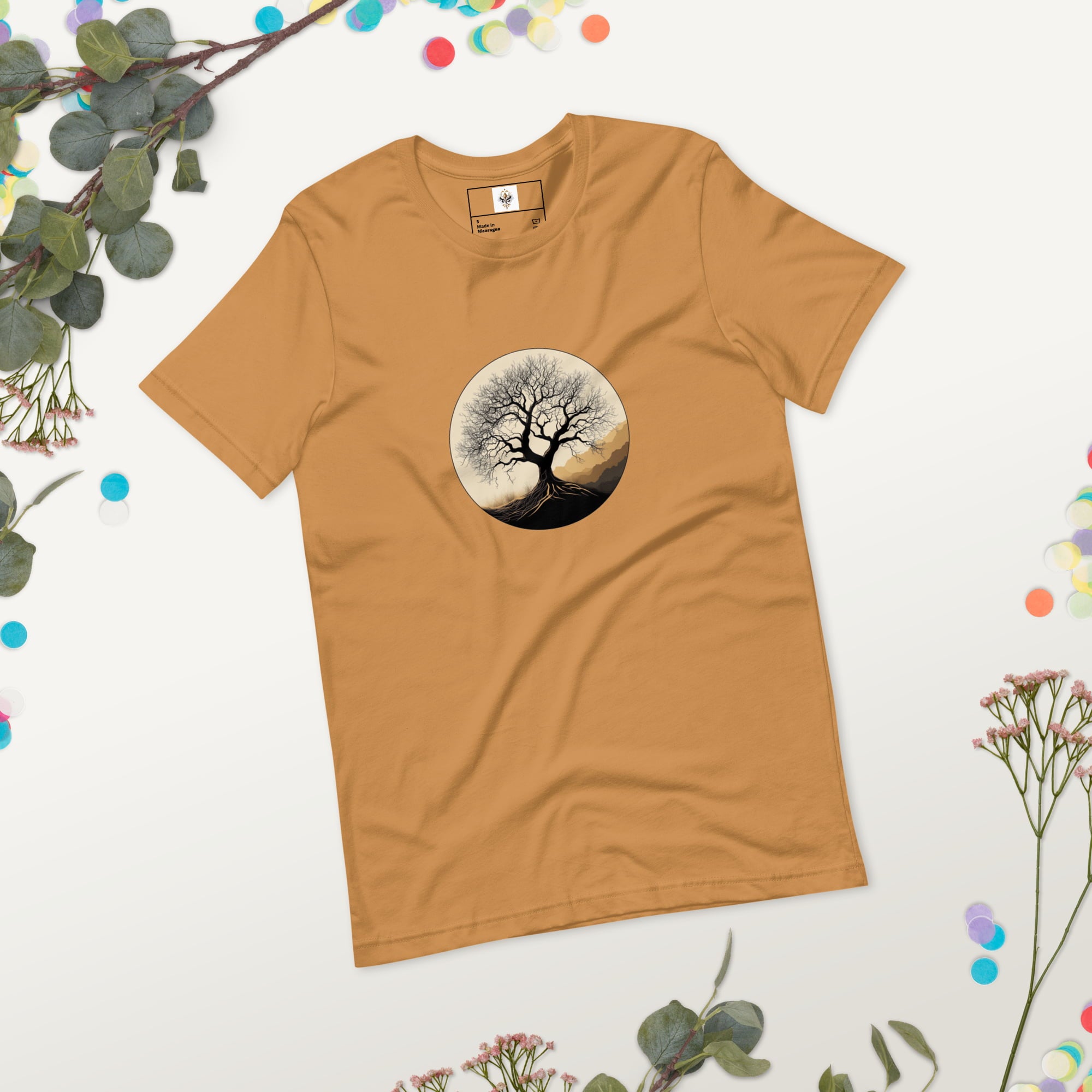 Roots of Life - Silhouette illustration of a bare tree with extensive roots, enclosed within a circle, featuring earthy tones and gentle mountains in the background. Graphic printed on toast-colored Unisex Staple T-Shirt Bella + Canvas 3001