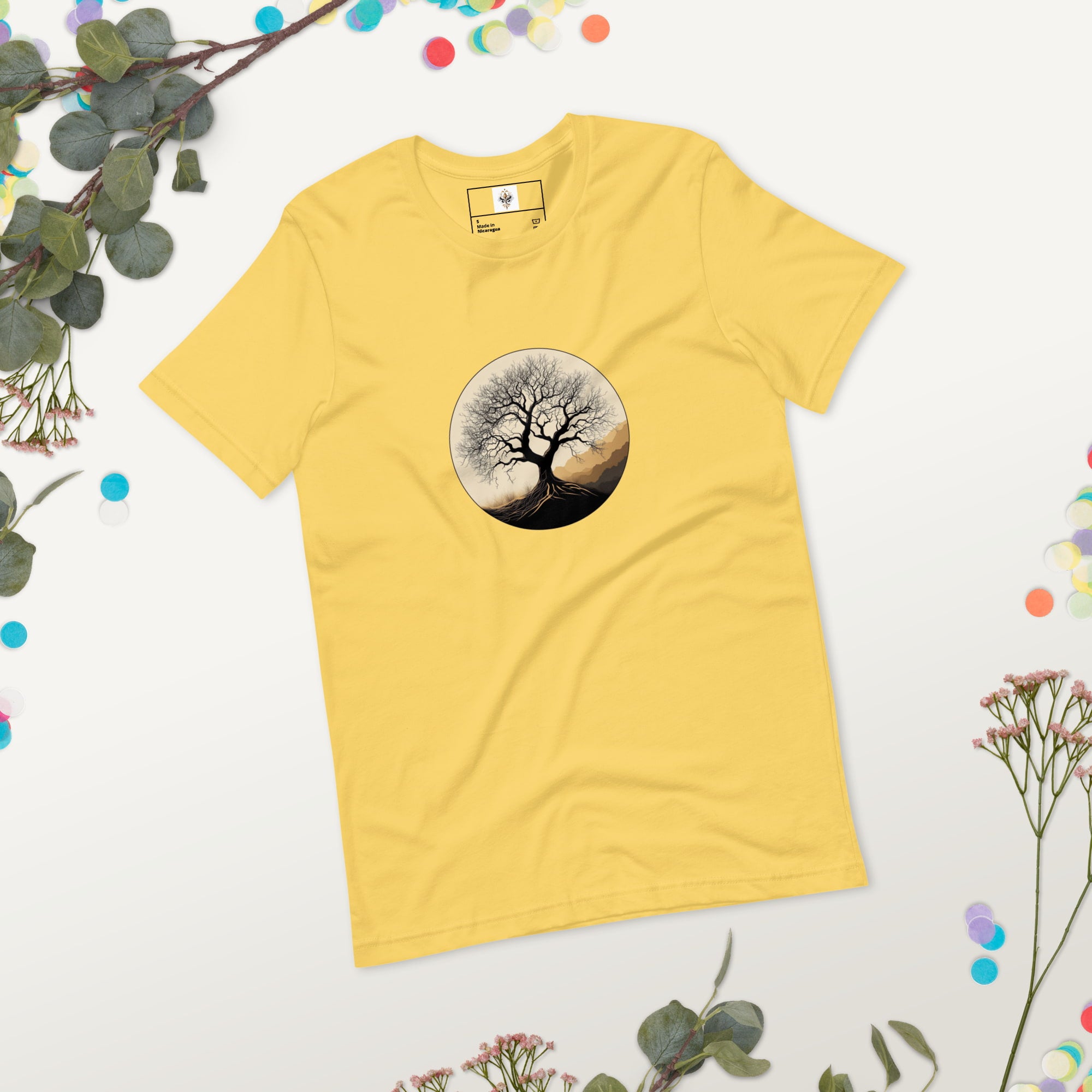 Roots of Life - Silhouette illustration of a bare tree with extensive roots, enclosed within a circle, featuring earthy tones and gentle mountains in the background. Graphic printed on yellow-colored Unisex Staple T-Shirt Bella + Canvas 3001